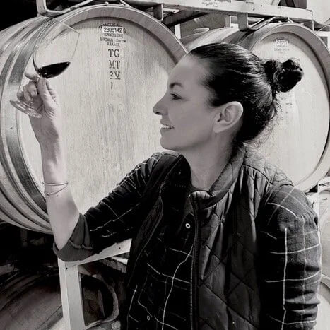 Olive Hamilton Russell examining a glass of wine in a barrel cellar
